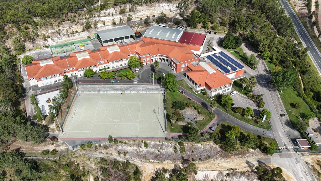 Foto aérea do campus da escola EITV, com os edifícios na parte superior e o campo de futebol na parte inferior.